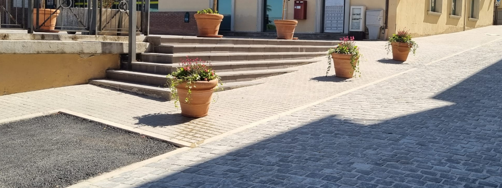 si vede un marciapiede con una scalinata e dei vasi di fiori